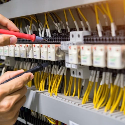 Electricians hands testing current  electric in control panel.